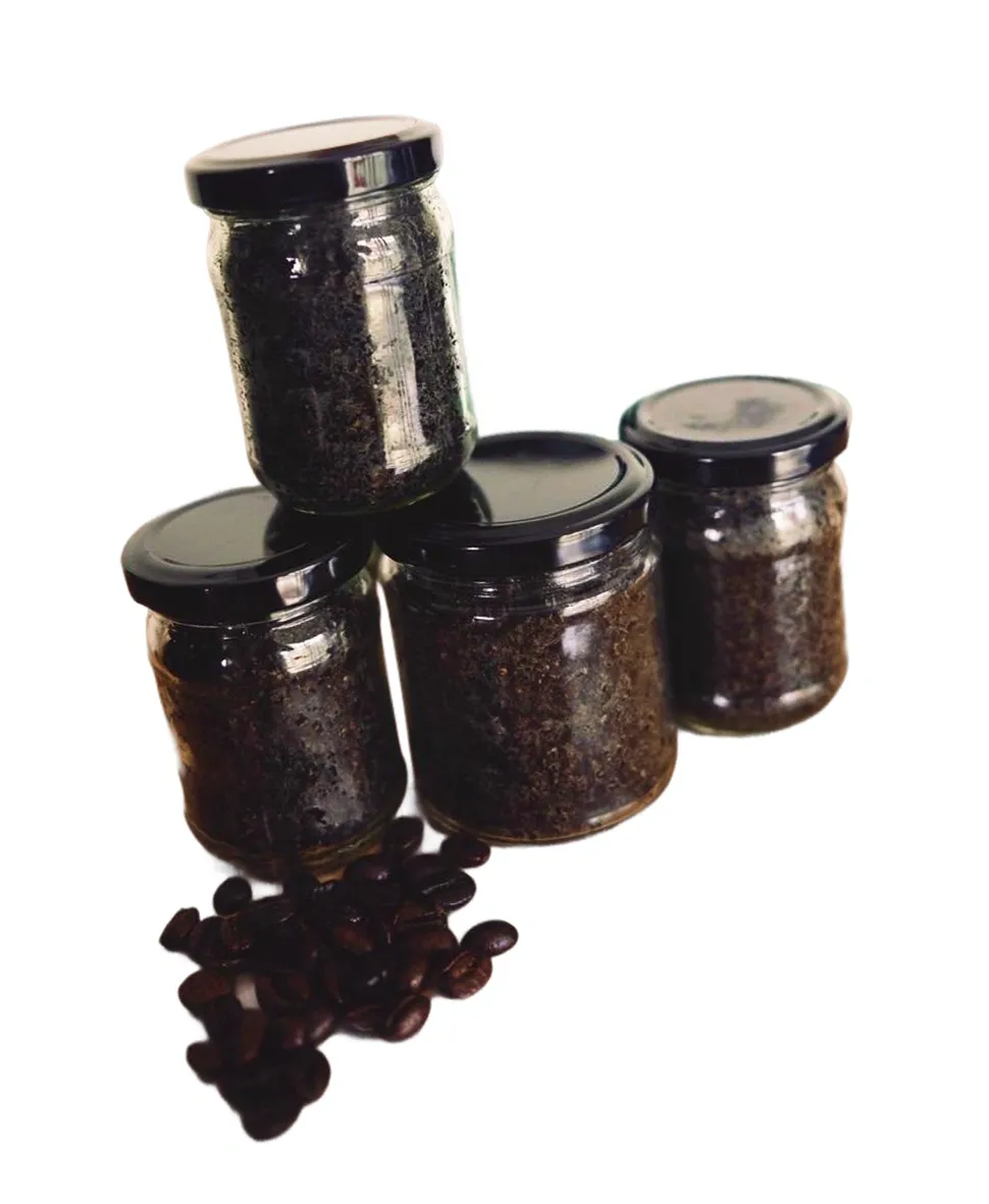 Glass jars filled with coffee scrub beside scattered coffee beans
